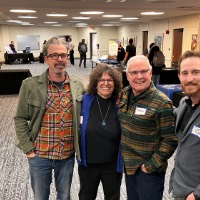Three men pose with Suzanne Zach, a faculty member for Film and Video.